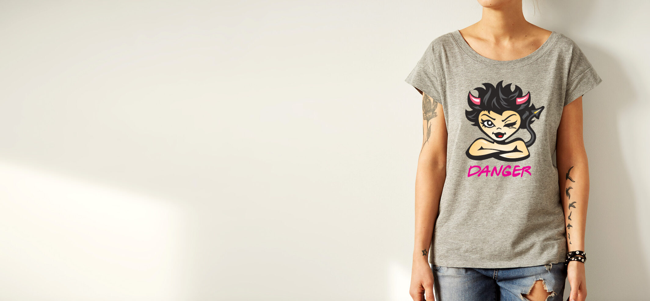 Young girl wearing grey blank t-shirt and blue jeans shorts. Concrete wall background with copy space for your text message or promotional content